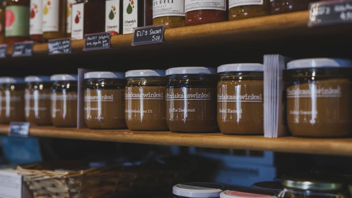 Close-up of artisanal food jars on wooden shelves in a local shop in Almere, Nederland.