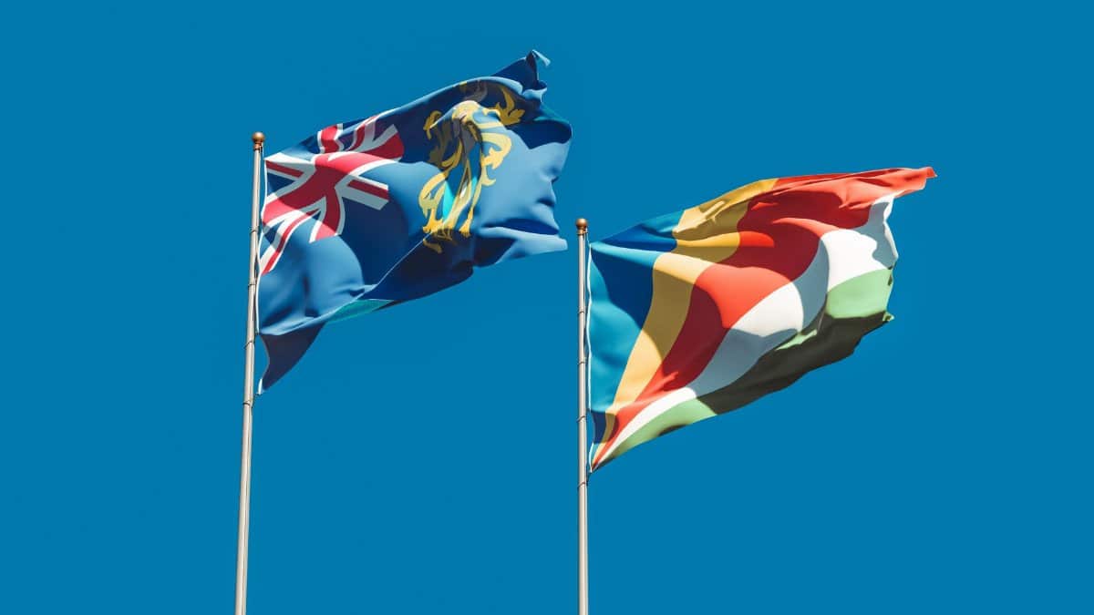 Vibrant flags of Tristan da Cunha and Seychelles waving under a clear blue sky.