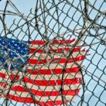 USA flag seen through barbed wire, symbolizing freedom and protection