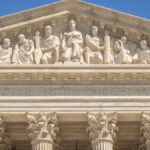 Detailed view of the Supreme Court Building's frontal frieze depicting historical figures and justices.