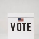 A minimalist ballot box with 'Vote' and an American flag, symbolizing elections.