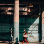 Street photography captures two women walking in La Habana, Cuba, both wearing masks, highlighting urban life.