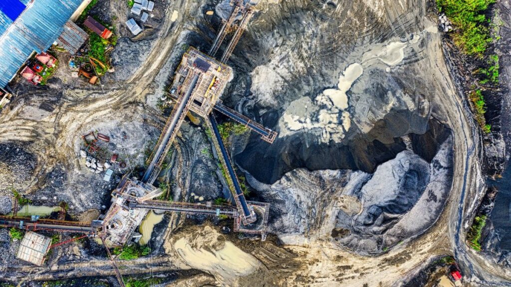 Top-down drone shot of an industrial mining site in Rumpin, West Java, showing machinery and excavation.