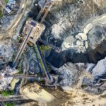 Top-down drone shot of an industrial mining site in Rumpin, West Java, showing machinery and excavation.