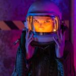 A woman in a space suit stands in a vividly lit space station, embodying futuristic exploration.