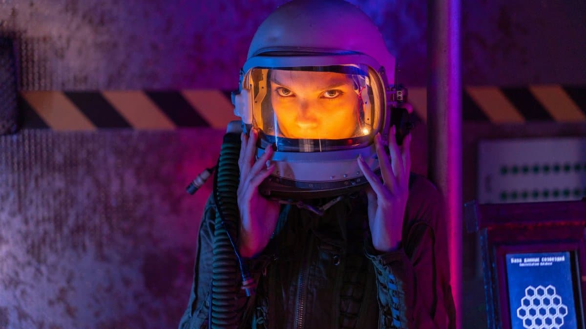 A woman in a space suit stands in a vividly lit space station, embodying futuristic exploration.