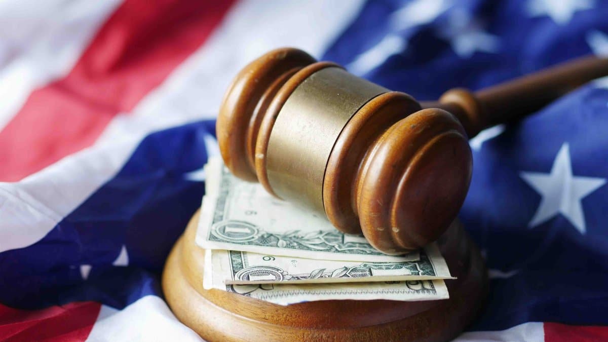 A gavel resting on dollar bills atop the American flag, symbolizing justice and finance.