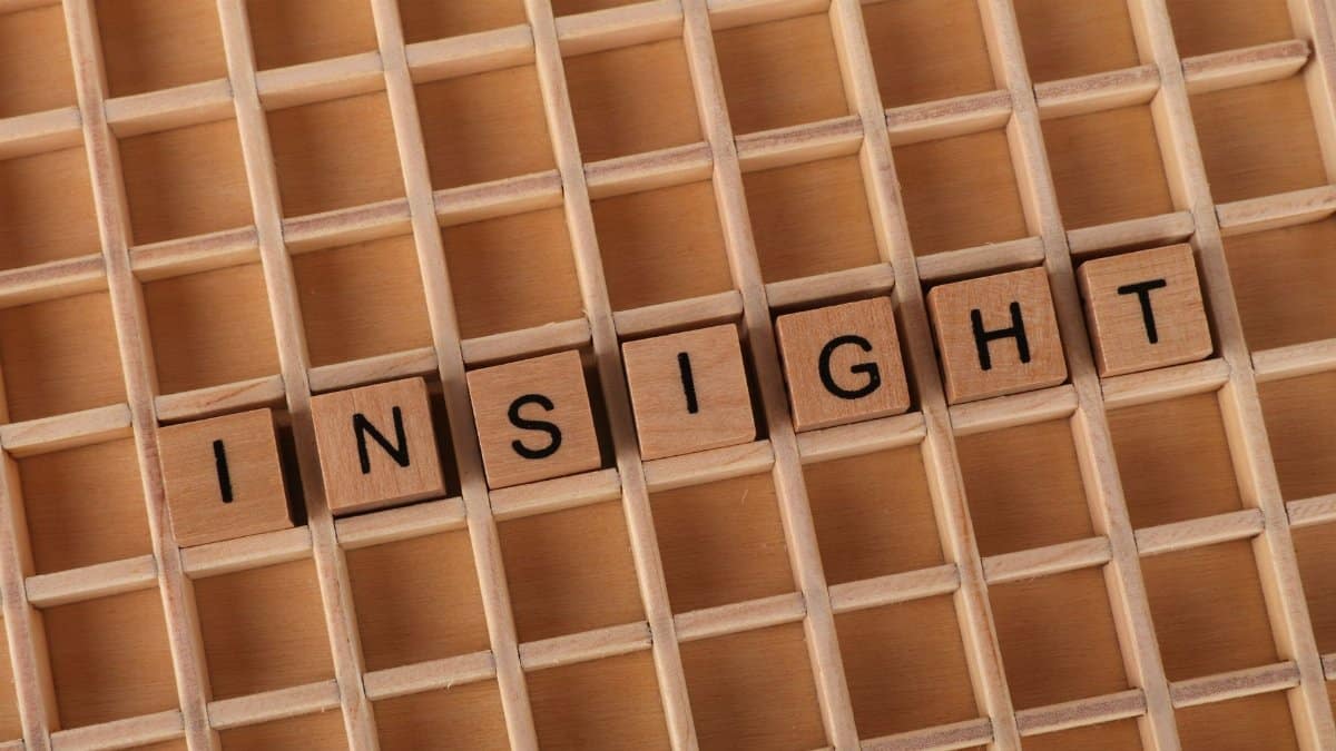 Scrabble letters spelling 'INSIGHT' on a wooden grid background, symbolizing understanding.