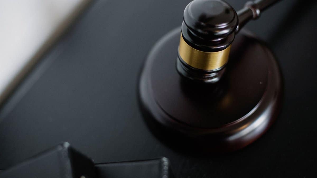 From above of wooden gavel on round surface near folders on table in courtroom