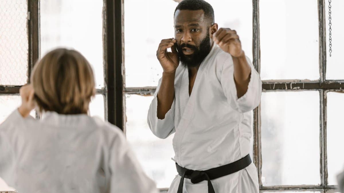 Martial arts fighters practice in a sunlit dojo, focusing on technique and discipline.