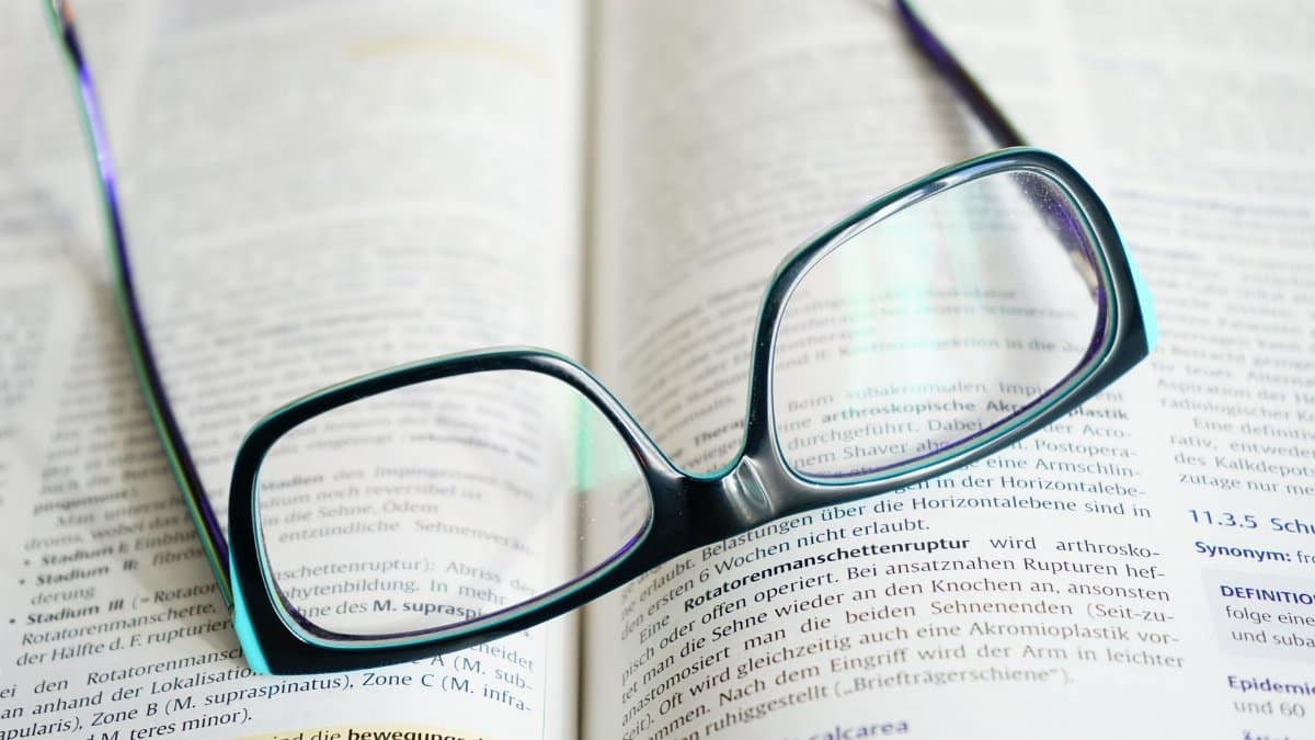 Reading glasses resting on an open textbook, symbolizing study and knowledge.