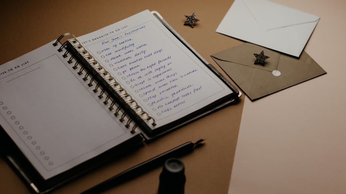 A tidy desk setup featuring a planner, to-do list, envelopes, and a pen.