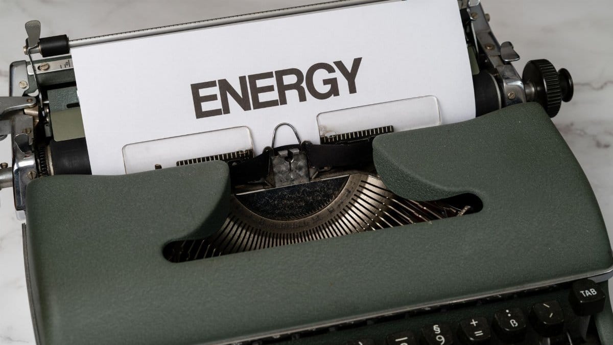 Close-up of a green vintage typewriter with paper showing the word 'Energy' in bold.