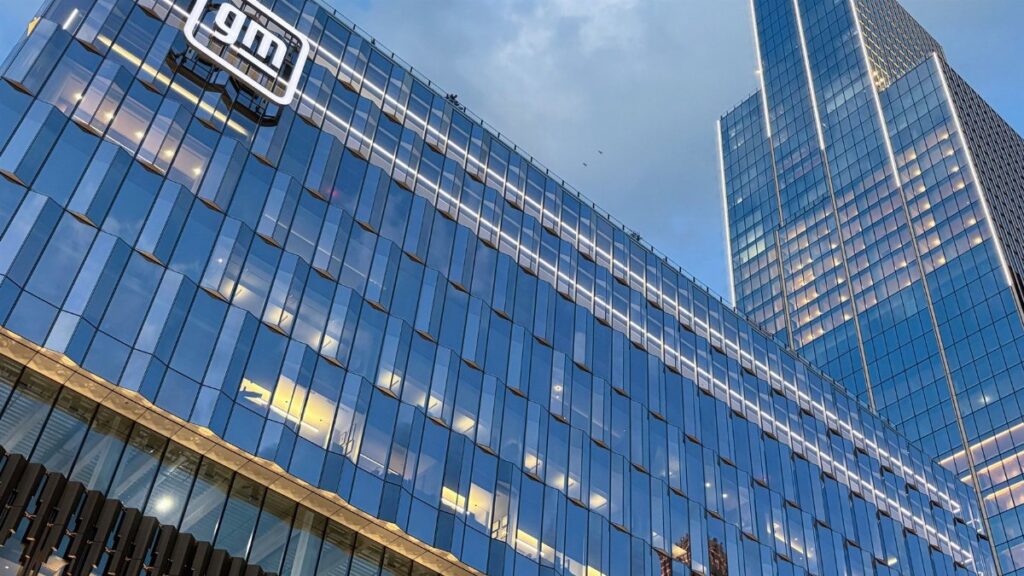 Modern skyscraper view of GM headquarters with glass facade reflecting sunset in Detroit.