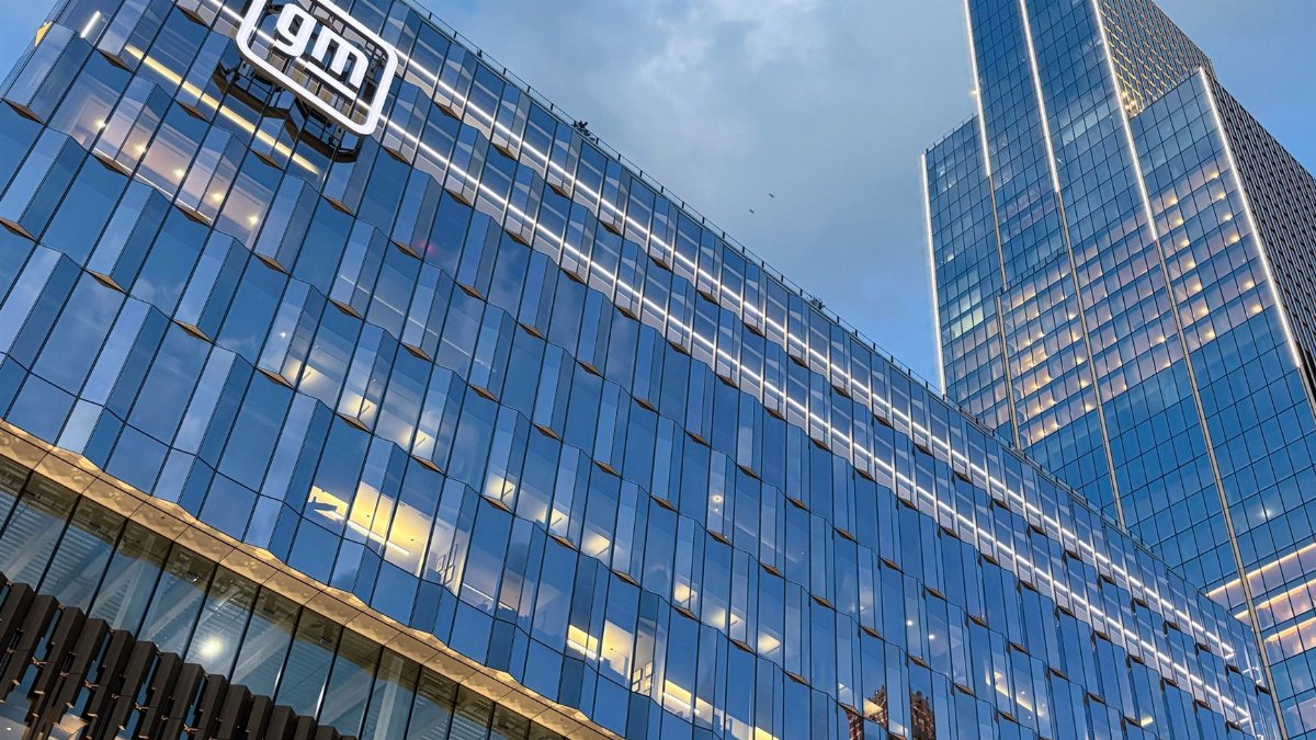 Modern skyscraper view of GM headquarters with glass facade reflecting sunset in Detroit.