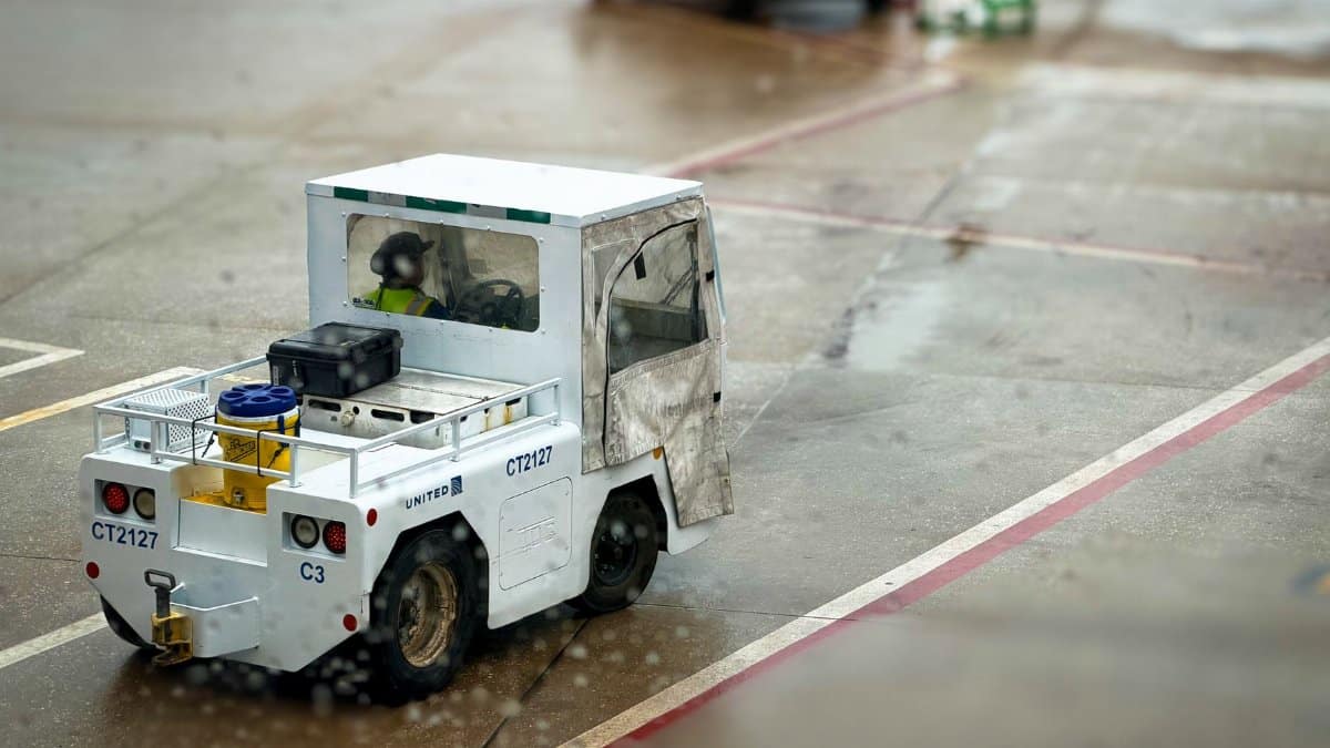 A small airport utility vehicle on a rainy tarmac, highlighting ground support operations.