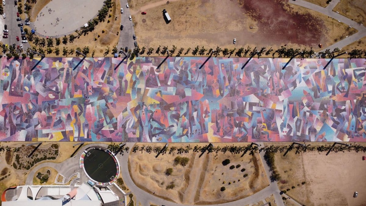 Colorful aerial view showcasing a decorated urban street with abstract patterns and surrounding landscape.