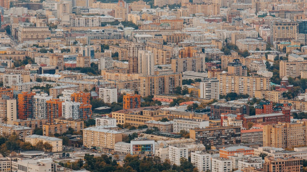 Expansive view of urban residential and commercial buildings from high above, showcasing city life.