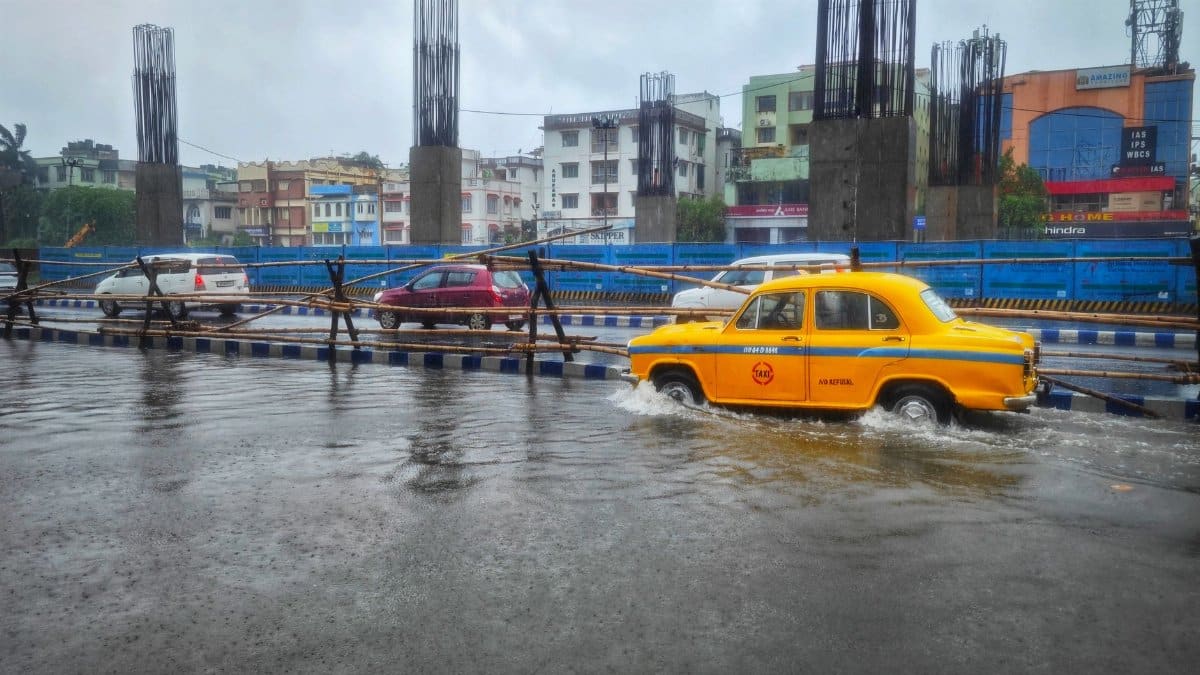 Yellow taxi navigating flooded streets in Kolkata, India, showcasing urban challenges.