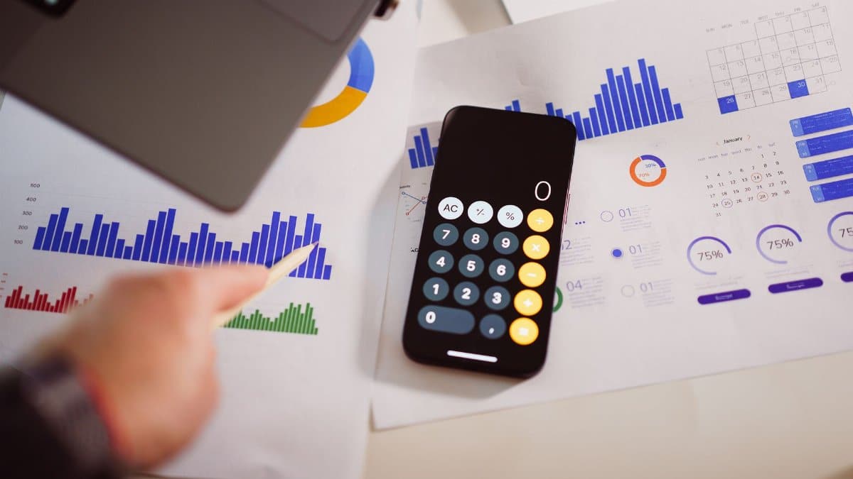 Business analytics setup with calculator, graphs, and laptop, showcasing financial insights.
