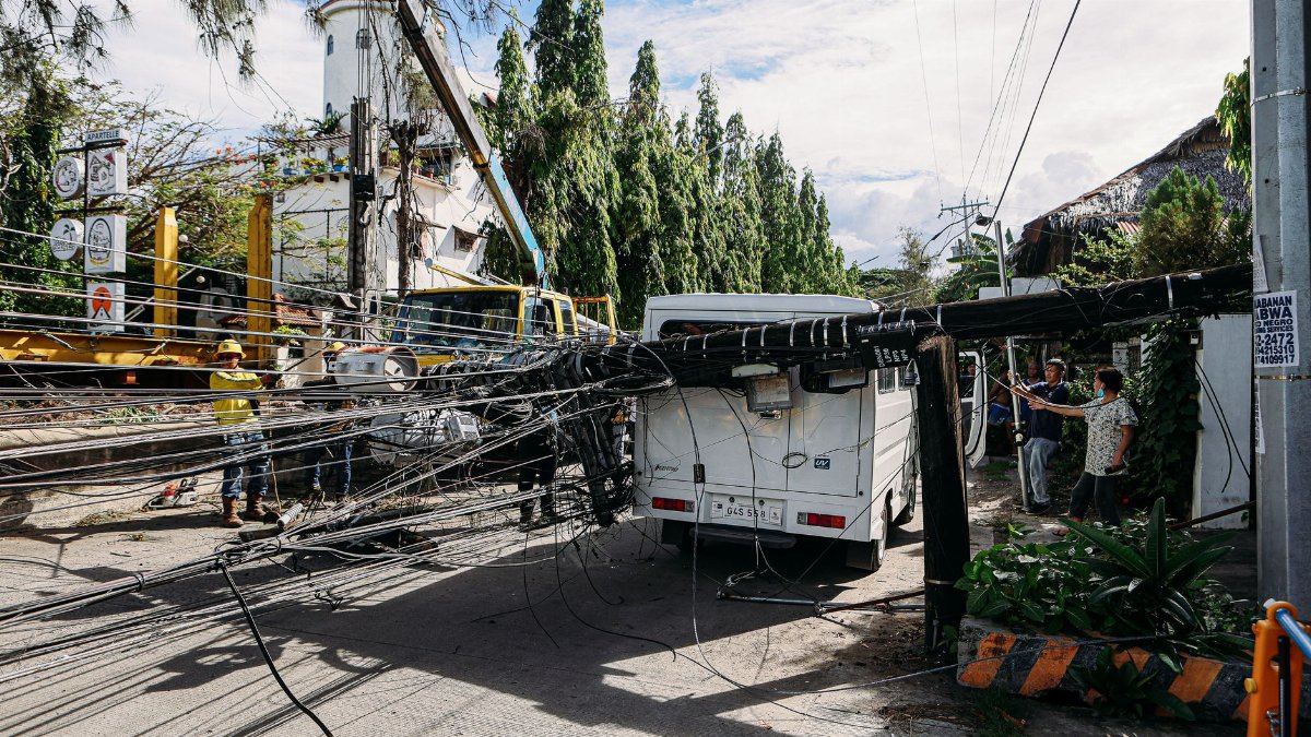 Utility crew working on damaged power lines after accident on a city street with a white van involved.