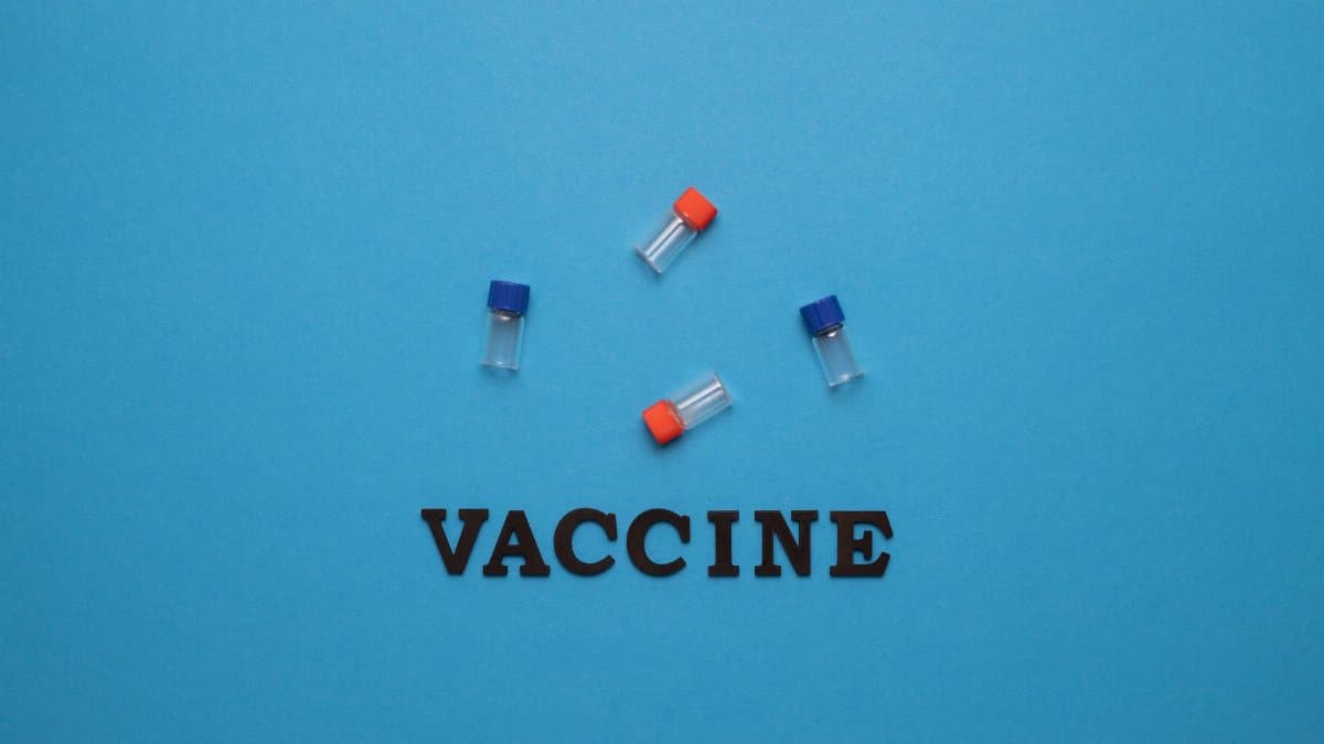Three small vials and the word 'VACCINE' on a blue background, representing vaccination and health.