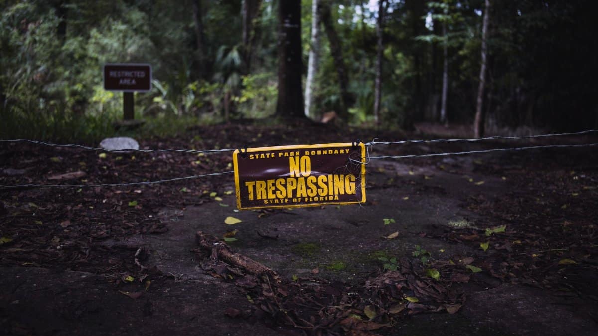 Vintage no trespassing sign on a forest path at state park boundary in Florida.