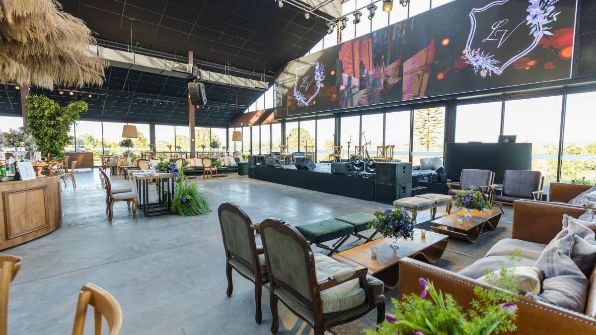 Spacious indoor event venue with elegant seating and stage setup, perfect for weddings and gatherings.