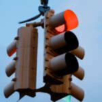 Close-up of a red traffic light signaling stop against a clear blue sky.