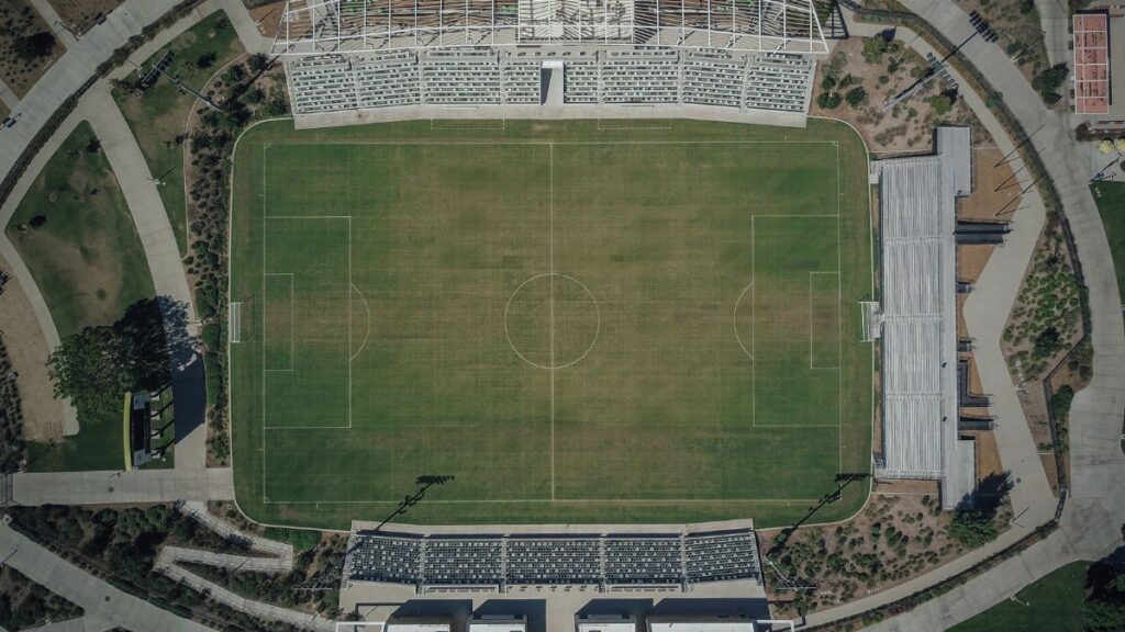 High-angle aerial shot capturing the details of a soccer stadium and surrounding sports complex.