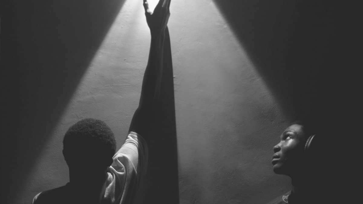 Two individuals in dramatic lighting expressing hope and aspiration.