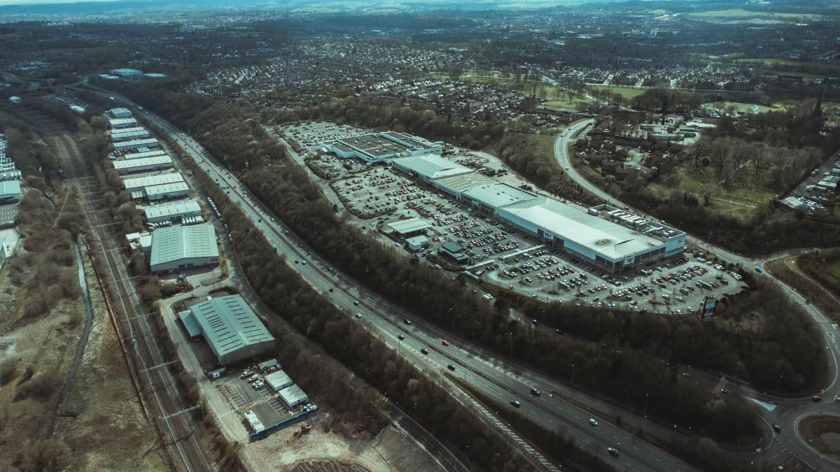 Aerial view of a bustling urban retail and industrial area with highways and parking lots.