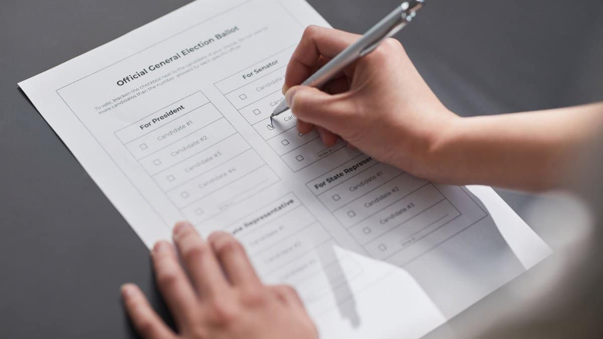 A close-up image of a hand marking an official election ballot with a pen, representing democratic voting.