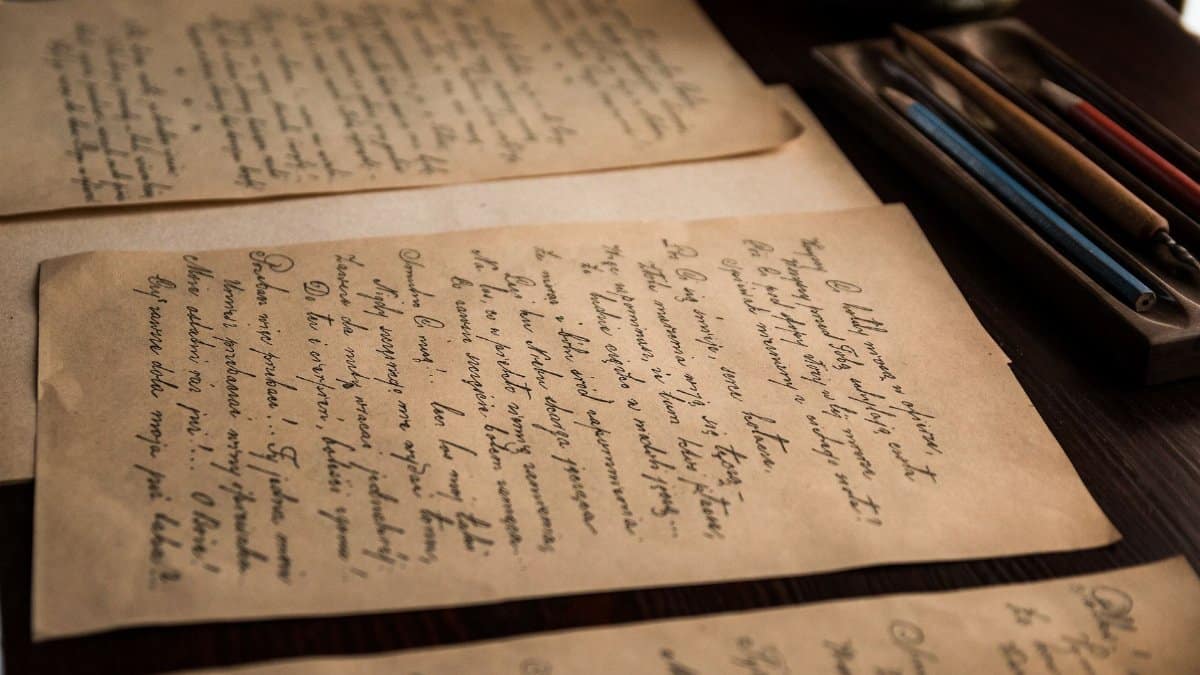 Authentic vintage handwritten letters on a rustic table with pens.