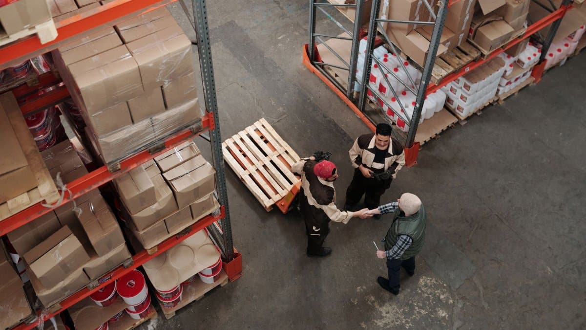 High angle view of workers shaking hands in a warehouse, symbolizing teamwork and logistics.