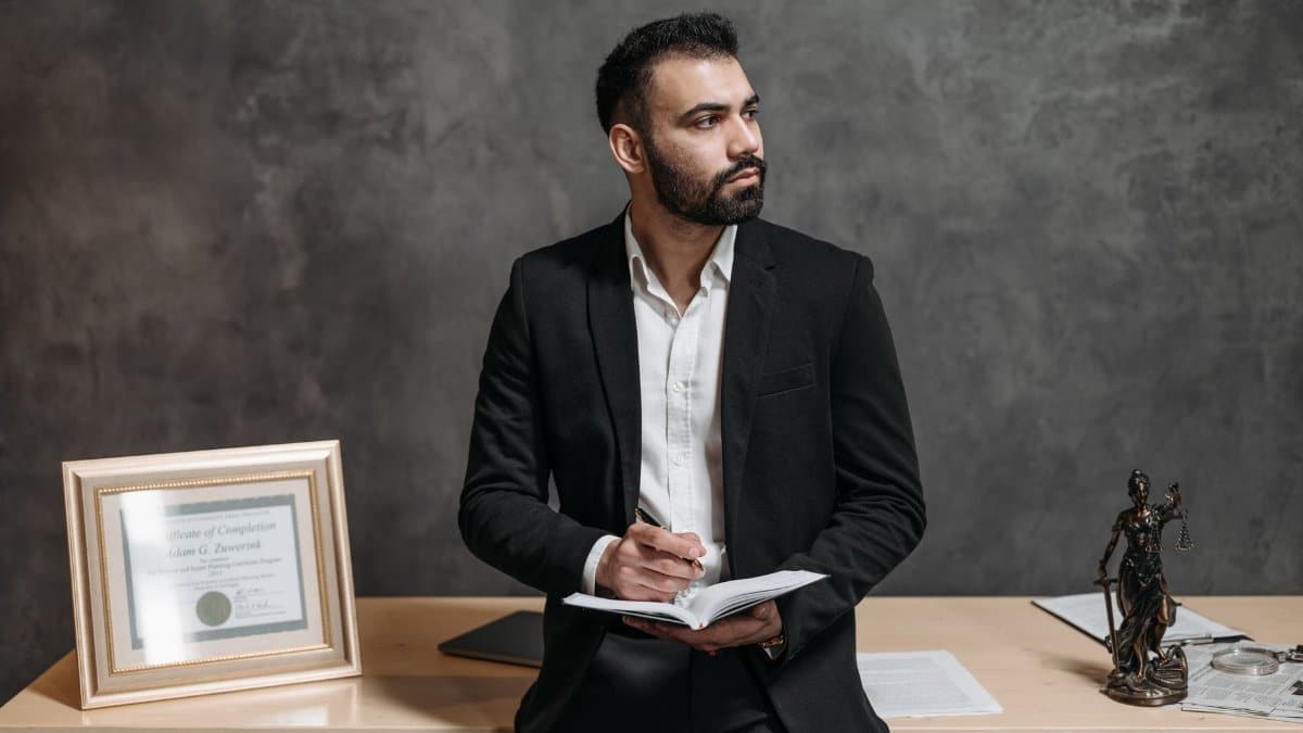 Confident male consultant takes notes, surrounded by legal paperwork in a modern office.