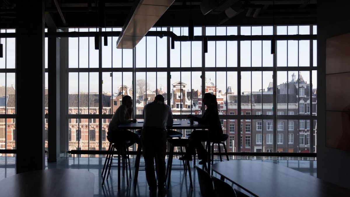 Silhouette of a business meeting in an Amsterdam office with cityscape view.