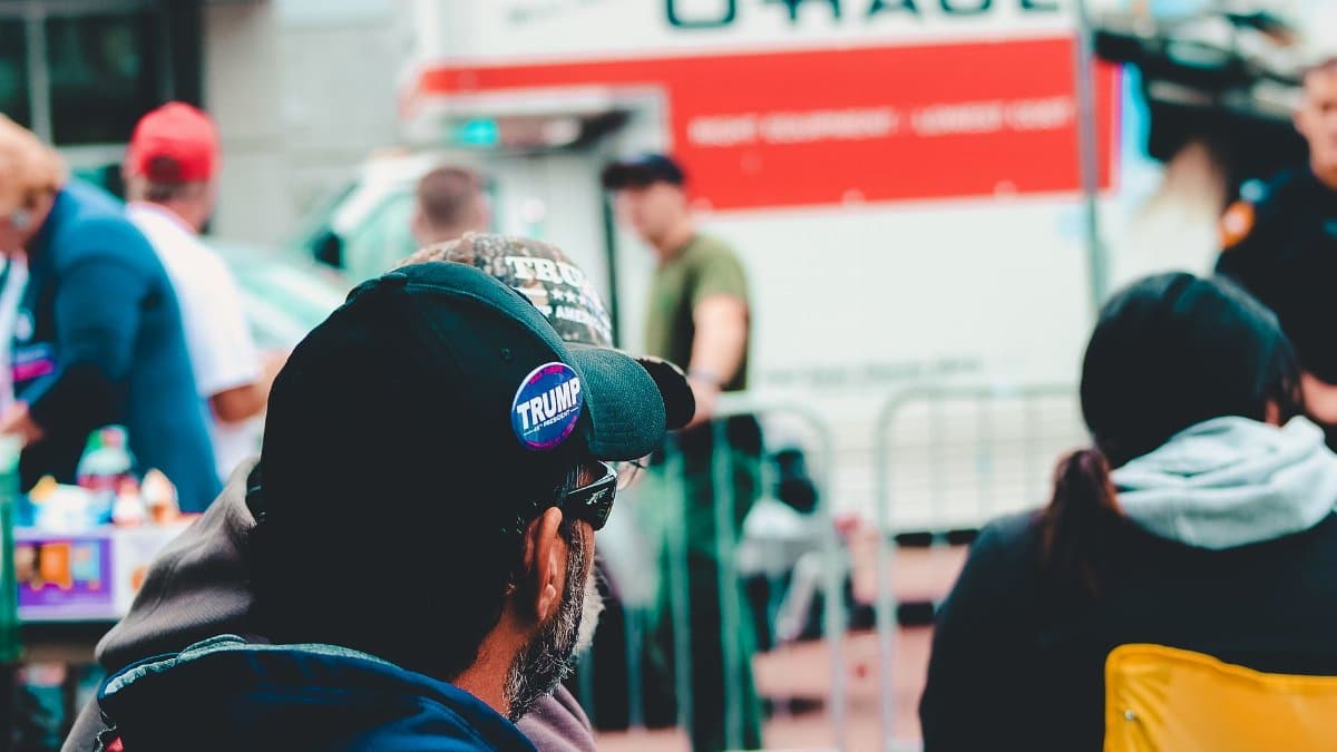 Participants at a political rally in Wheeling, WV wearing campaign merchandise with a U-Haul in the background.