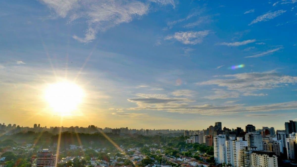 Capture of a vibrant cityscape with sun glare and a clear blue sky, showcasing modern urban architecture.