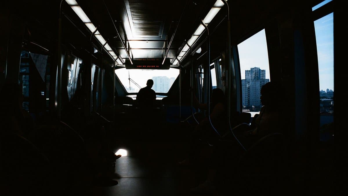 Atmospheric silhouette of commuters inside a train during daytime travel, highlighting urban transit.