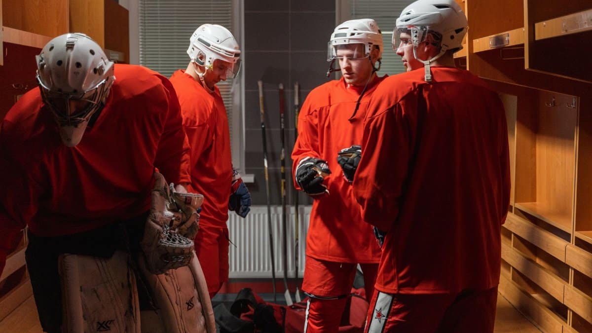 Ice hockey team in red uniforms preparing in the locker room before a game.
