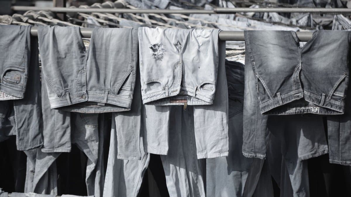 A collection of worn denim jeans hanging to dry on outdoor racks, creating a rustic and vintage vibe.