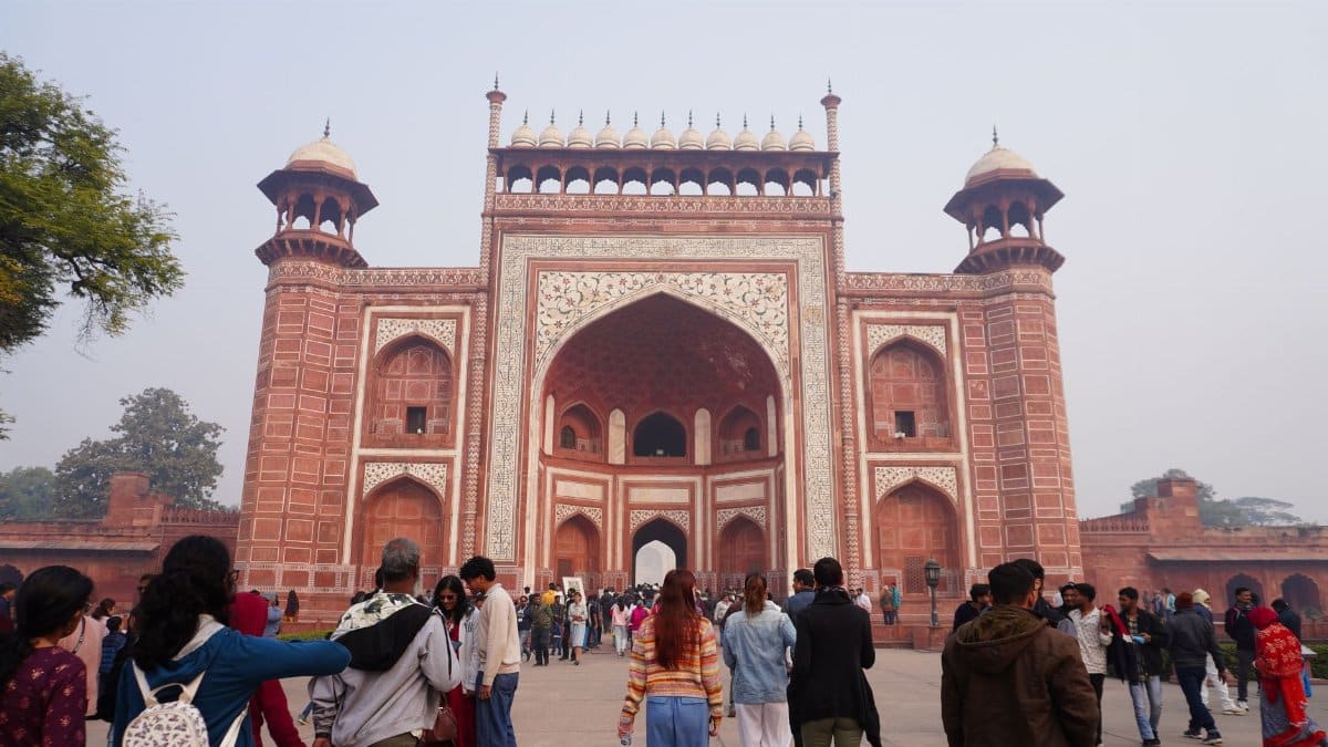 Crowd of visitors at the grand entrance of Agra Fort on a clear day.