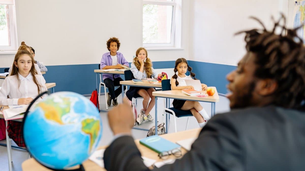 A diverse group of students and their teacher engaged in a classroom discussion with a globe on the table.