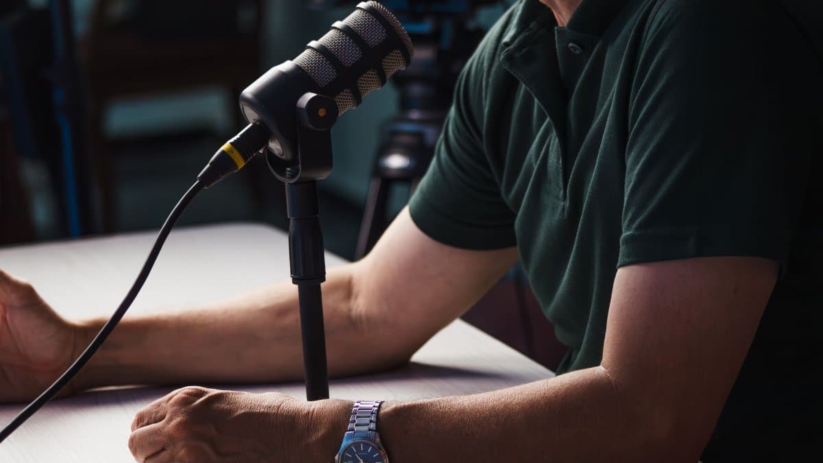 Close-up of a person recording a podcast in a studio, featuring a microphone and professional audio equipment.