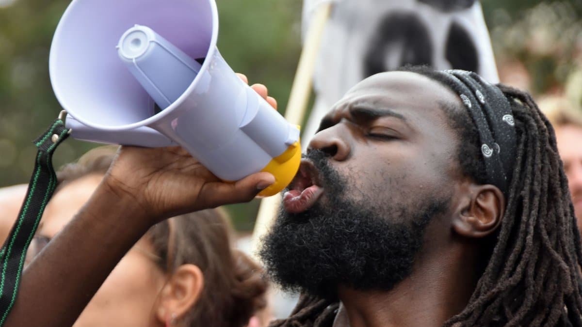 Black man passionately shouting into a megaphone during a protest in Lisbon, Portugal.