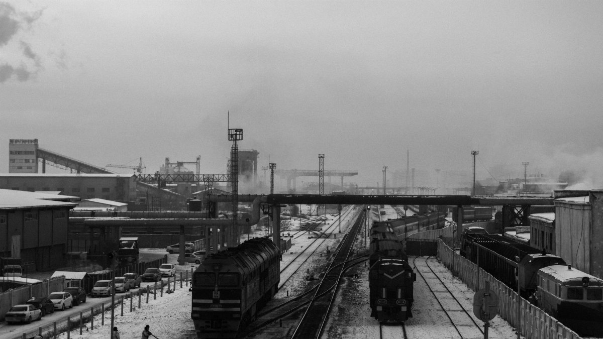 Black and white photo of Ulaanbaatar railway in winter, showcasing industry and public transport.