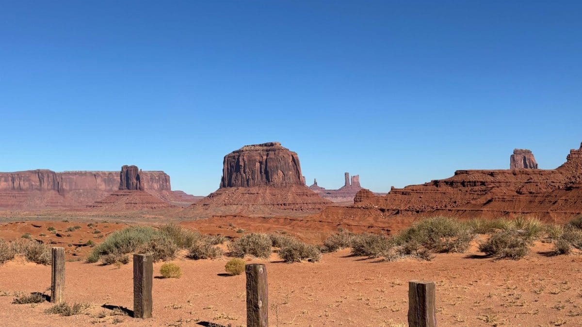 Stunning shot of iconic Monument Valley rock formations and desert landscape under a clear blue sky.