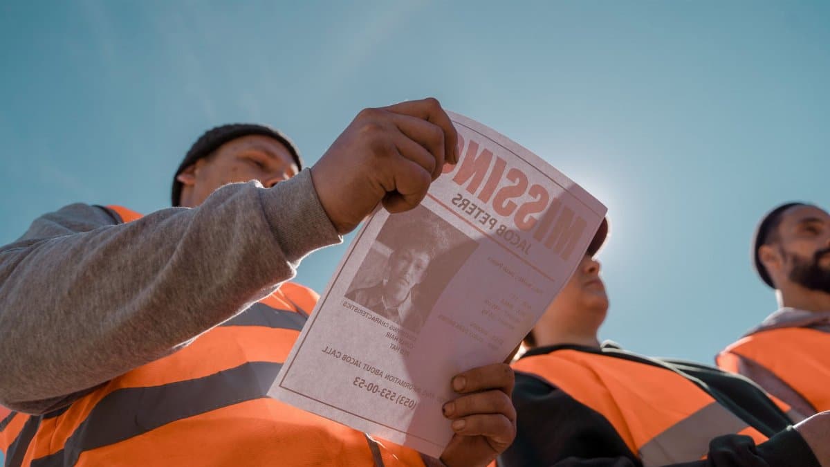 A group of volunteers distributing missing person flyers while conducting a search outdoors in bright daylight.