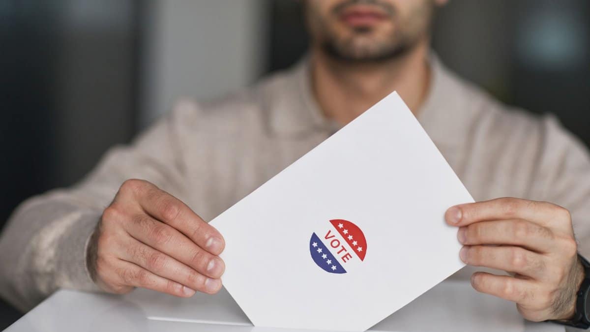 A man holds a voting envelope with a vote sticker. Symbolizes election participation.